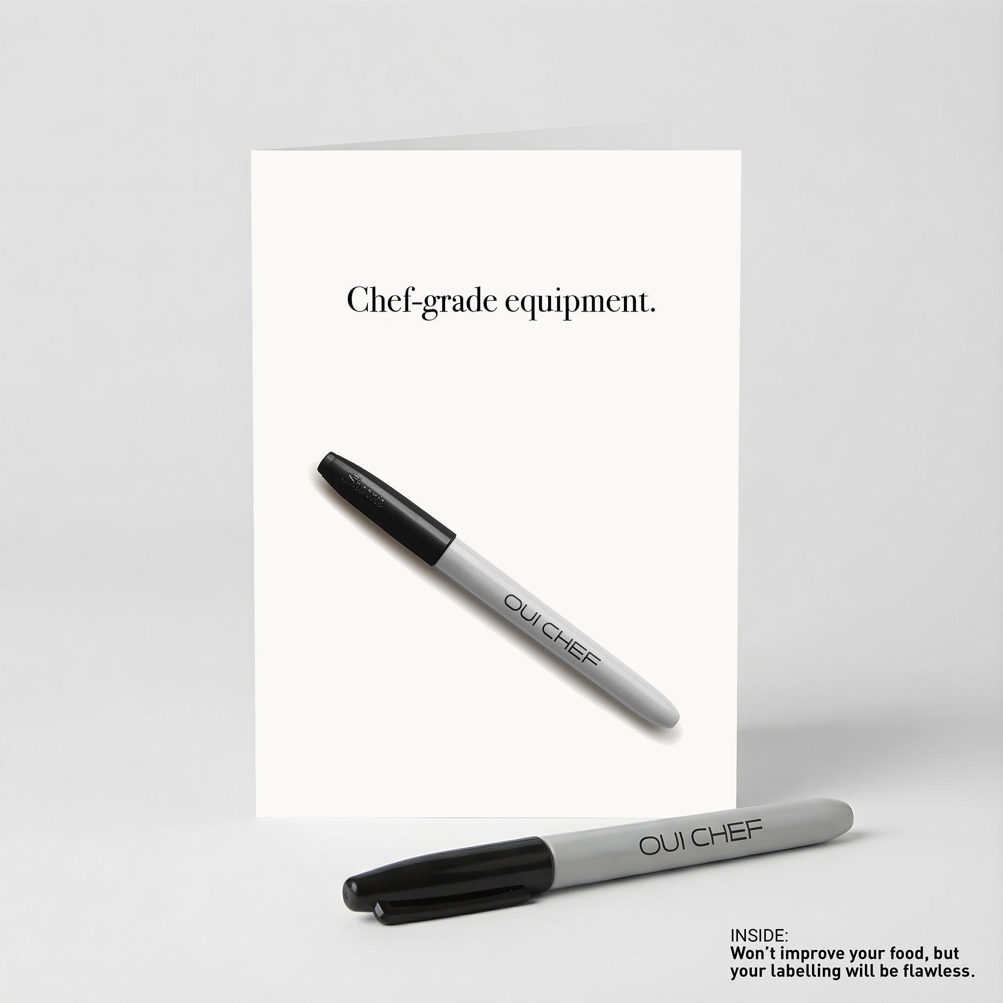 Oui Chef "Chef-Grade Equipment" Greeting card standing against a white background with a sharpie placed beside it.