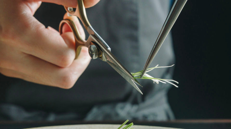 Chef's hands trimming herbs held by tweezers with Oui Chef SuperSharp scissors 